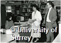 Photographs of people talking to a member of staff at the Information Desk in the University of Surrey Library and a drinks reception in the art gallery