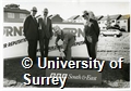 Photograph taken during the turf cutting ceremony for the radio station at the University of Surrey Stag Hill Campus. Caption says 'Keith Clement, Head of Broadcasting, BBC South & East, cutting the turf for the new purpose-built local radio station based on the University campus. L/R: Geoffrey Osborne, Vice-Chancellor, Keith Clement and John Oliver, Managing Director, Geoffrey Osborne Building Ltd'