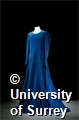 The dress is lined with a heavy cotton and the outer material is thick bright blue velvet.
It has a v-neck and darts down the front to give a fitted effect. There are hook and eye fastenings from the beck of the neck to the lower waist. It has long sleeves that have two popper fastenings on the inside cuff and meet at a point over the top of the hand. It has a very full floor length skirt.
There is some staining down the front of the skirt.