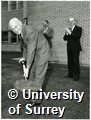 Photograph of the turf cutting ceremony at the site of the Wolfson Cytotechnology Laboratory. Caption says 'Sir Austin Pearce, Pro-Chancellor of the University of Surrey and Chairman of British Aerospace, cutting the first turf on the site of the Cytotechnology Laboratory at the University. In the background, from l/r Dr Anthony Kelly, Vice-Chancellor of the University and Mr Ray Botterell, Managing Director of Scientific Lesser Ltd'