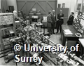 Photograph of academic staff in the department of Electronic and Electrical Engineering at the University of Surrey. Caption on reverse says 'From l/r: Dr B J Sealy, Reader and Head of the Solid State Devices and Ion Beam Technology Group, University of Surrey; Professor A D S Barr, Sir Robert Clayton CBE, both members of the UGC Technology Sub Committee, and Dr R Seebold, Senior Industrial Tutor, Department of Electronic and Electrical Engineering, in the D R Chick Accelerator Laboratory'